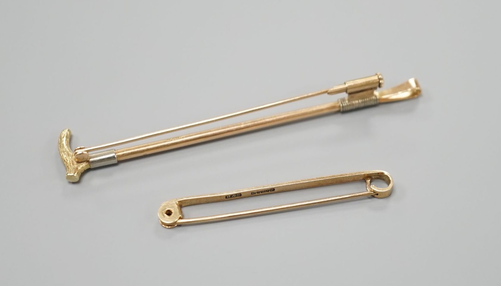 A yellow metal riding crop brooch, 69mm and a 9ct gold tie pin, gross 6.6 grams.